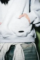 Hoodie de algodón color gris melange, con diseño de costuras decorativas en contraste blanco en el pecho y mangas. Presenta capucha, bolsillo tipo canguro frontal y puños y ruedo acanalados.