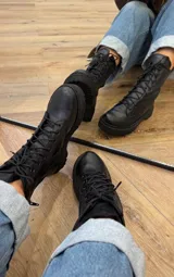 Botas de cuero negras con cordones, suela track y cierre lateral.