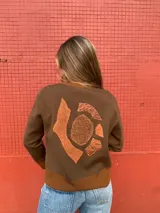 Cárdigan marrón de lana merino con cuello redondo, cierre frontal con botones y ribete en contraste color marrón claro en cuello, puños y ruedo.