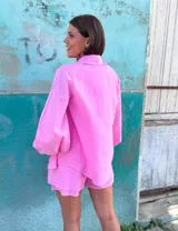 Conjunto de dos piezas confeccionado en lino color blanco. Incluye una camisa de corte holgado con mangas abullonadas y bolsillos frontales, y un short de tiro alto con cintura elástica y forro interior.