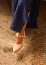 Sandalias de gamuza color beige con punta fina reforzada con detalle metálico, taco cuadrado y pulsera ajustable al tobillo.