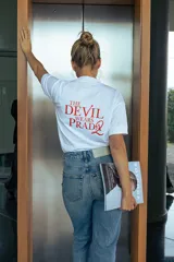 Remera blanca de manga corta con cuello redondo, confeccionada en algodón orgánico. Presenta un estampado gráfico en la espalda con la frase 'The Devil Wears Prada' en color rojo.