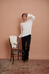 Blusa blanca de manga larga con puntilla de flores en el escote y volado en el ruedo.