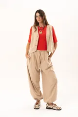 Pantalon tipo babucha de color beige, con silueta relajada y acabado suave tipo piel de durazno. Presenta cintura regulable con cordón y elástico en los tobillos que genera una forma abuchonada.