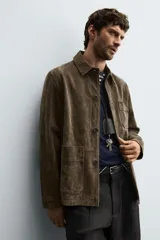 Sobrecamisa de corte regular confeccionada en piel con acabado serraje. Presenta cuello solapa, cierre frontal con botones y bolsillos de plastrón en el pecho y la parte inferior.