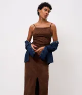 Vestido midi de gamuza sintética color marrón, con diseño de bordado de follaje en relieve. Presenta escote recto, tirantes finos regulables, ajuste al cuerpo, espalda con lastex y abertura frontal en la falda.