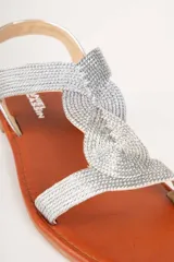 Sandalias plateadas con tiras finas entrecruzadas y cierre con hebilla en el tobillo.