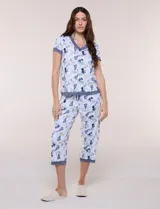 Conjunto pijama de pantalón capri y remera René Rofé, de color blanco con estampado floral en tonos azules y celestes. Remera de manga corta con escote en V y detalles de encaje azul en el escote, las mangas y el ruedo. Pantalón capri con cintura elastizada, cordón de ajuste y encaje en el ruedo.