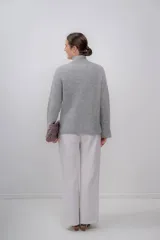 Polera gris de tejido de punto grueso, con cuello alto y mangas largas.