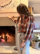 Camisa de color marrón oscuro con cuello clásico y mangas abullonadas con puños elásticos. Presenta un corte holgado y cierre frontal con botones.