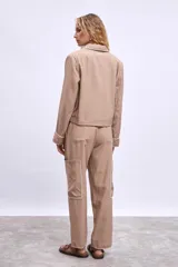 Pantalón cargo color beige con bolsillos laterales y bordados en hilo blanco en contorno de bolsillos y ruedo.