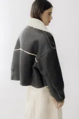 Campera de cuero negro con interior de piel sintética, cuello solapa, cierre frontal con botones y bolsillos delanteros.