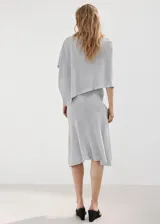 Poncho gris de punto con diseño asimétrico de capa, cuello barco y mangas tres cuartos.