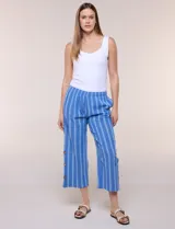 Pantalón de algodón rústico azul a rayas, de tiro medio-alto con pretina elastizada y corte wide leg de largo cropped. Cuenta con bolsillos laterales y detalle de abertura en el ruedo con tres botones de madera.