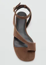 Sandalias planas de gamuza marrón, con diseño de tiras cruzadas, separador de dedo y tira ajustable en el tobillo con hebilla metálica.
