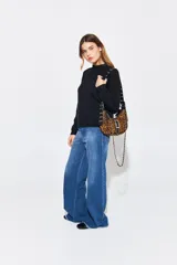 Cartera tipo baguette negra de cuero vacuno con textura tipo piel de cocodrilo. Tiene correa de cuero ajustable con detalles de tachas y cadena metálica plateada. El frente presenta un aplique de cuero con hebilla metálica plateada con tachas.