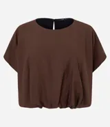 Blusa corta de estilo balonê confeccionada en tejido de viscosa, con mangas cortas amplias, escote redondo y ruedo fruncido que genera un efecto voluminoso.