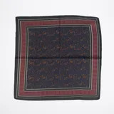 Pañuelo cuadrado de seda azul marino con estampado de cachemir en tonos naranja y verde. Tiene un borde con un diseño geométrico en tonos burdeos y negro.