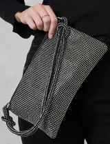 Cartera de strass color negro, con cierre metálico y bolsillo interior. Incluye una correa de mano trenzada y un cierre de cremallera.
