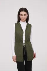 Chaleco largo sin mangas de tejido de punto color negro, con capucha y lazo ajustable en la cintura. Presenta bolsillos frontales y diseño abierto.