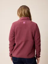 Canguro de sherpa color bordó, con cuello alto y cierre frontal parcial. Presenta un bolsillo con cierre en el pecho y bolsillos laterales, confeccionado en tejido de textura suave y abrigada.