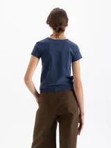 Remera de corte ajustado al cuerpo, color azul con efecto lavado, cuello redondo y mangas cortas. Presenta una estampa frontal de dos cisnes enfrentados y logo bordado en la espalda.