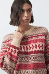 Sweater de punto con diseño jacquard de inspiración nórdica, cuello redondo y mangas largas. Presenta un patrón geométrico en tonos tierra, azul y blanco, con puños y ruedo acanalados.
