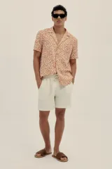 Camisa de manga corta con cuello camp color arena con estampado de manchas color naranja.