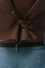 Chaleco sastrero de lino color negro con escote en V, cierre frontal de un botón y tiras ajustables en la espalda.