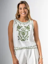 Musculosa blanca con bordado floral verde, cuello redondo y corte holgado.