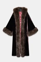 Abrigo largo de terciopelo en tono marrón oscuro, con cuello solapa y puños adornados con aplicación de pelo sintético. Presenta un diseño abierto con forro interior en color rojo con estampado floral.