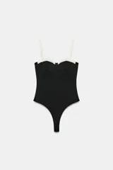 Body negro con diseño estructurado, escote corazón con aros y detalles en color blanco contrastante en la parte superior y en los tirantes finos ajustables.