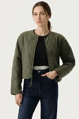 Campera corta acolchada de diseño matelasse, color verde oliva, con cuello redondo, cierre frontal y mangas largas.