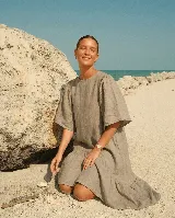 Vestido largo de lino color beige, con mangas abullonadas y volado inferior asimétrico, más largo en la parte trasera.