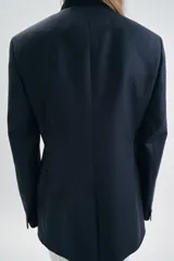 Blazer entallada de Zara Woman Collection, color azul marino, con cuello subido y detalle de tejido a contraste. Presenta cierre frontal cruzado con botones, manga larga y bolsillos con solapa en el delantero. Incluye forro interior.