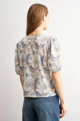 Camisa manga corta con estampado paisley en tonos azules y marrones, escote en V y cierre frontal con botones.