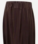 Pantalón de corte aladino confeccionado en viscosa y poliéster, con diseño de rayas verticales y acabado con leve transparencia. Presenta cintura alta, trabillas para cinturón y puños elásticos en el dobladillo.