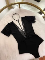 Body entallado de lycra color negro, con escote pronunciado decorado con encaje y microtul. Presenta mangas cortas de encaje y un collarín regulable desmontable integrado al diseño.