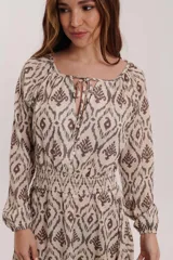 Vestido largo color crudo con estampado abstracto en tonos marrones y grises. Escote cuadrado con lazo ajustable, mangas largas y falda con elástico en la cintura.