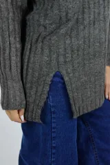 Buzo de punto beige melange, de diseño largo y holgado, con cuello alto, mangas largas y aberturas laterales en el dobladillo.