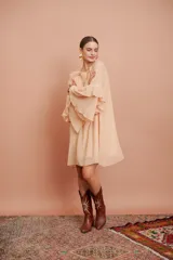 Vestido corto color salmón claro, de mangas largas con volados y corte suelto.