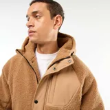Campera con capucha color beige, con efecto borreguito en el cuerpo y las mangas, y detalles en tela lisa beige en los hombros y el pecho. Tiene cierre frontal y botones a presión.
