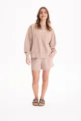 Buzo deportivo sin frisa de color beige con efecto lavado, cuello redondo, mangas largas y estampa frontal con texto bordado.