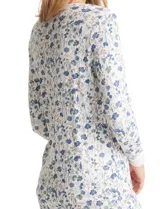 Conjunto de pijama compuesto por una remera de manga larga con escote redondo y cierre frontal de botones, y un pantalón con cintura elástica y lazo de ajuste. Presenta un estampado floral en tonos azules sobre fondo blanco.