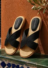 Sandalias planas marca Zingara con tiras cruzadas negras de textura trenzada y plantilla de rafia con talón en eco-cuero negro.