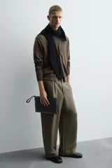 Bolso tipo sobre color verde oscuro, con asa de mano, compartimento principal con cierre de cremallera, bolsillo interno con cremallera y bolsillo frontal con cremallera.