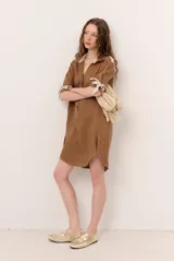 Vestido corto de lino con cuello polo, escote en V con botones y mangas cortas con detalle de tiras para atar en los puños. Presenta costuras a contratono y dobladillo curvo con aberturas laterales.