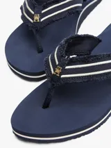 Ojotas Tommy Hilfiger azul marino con tiras de tela trenzada con rayas blancas y suela plana.