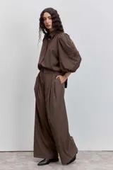 Camisa de color marrón con cuello clásico, mangas abullonadas y detalle de bordado floral en una de las mangas.