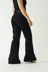 Pantalón negro de tiro medio, corte ajustado en la cadera y piernas que se ensanchan. Presenta cortes en el bajo de cada pierna.